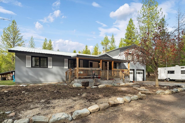 ranch-style home with covered porch, an attached garage, and metal roof