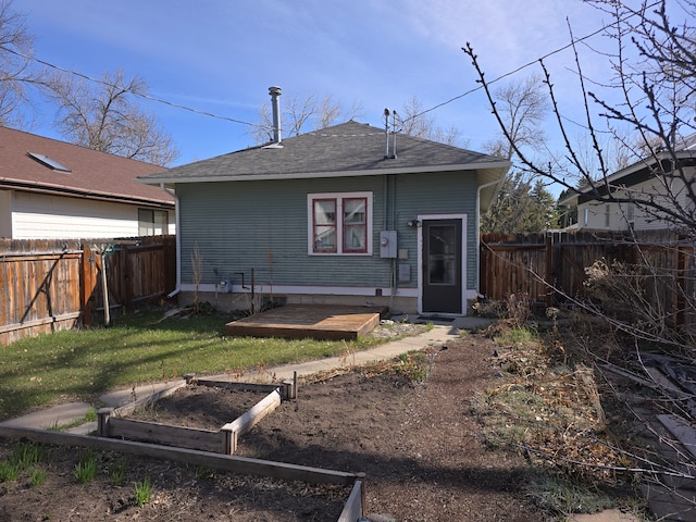 324 1st Ave NW, Choteau, MT 59422 - rear view of house featuring a garden, roof with shingles, a yard, and a fenced backyard