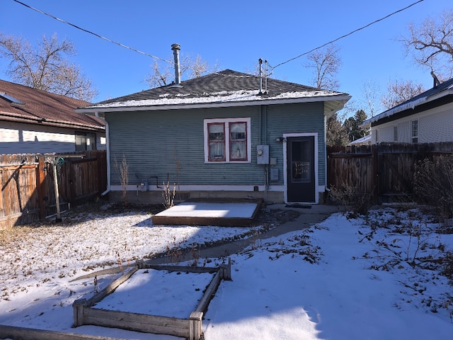 snow covered rear of property featuring a fenced backyard