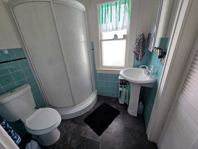 324 1st Ave NW, Choteau, MT 59422 - bathroom featuring a wainscoted wall, toilet, a sink, tile walls, and a stall shower