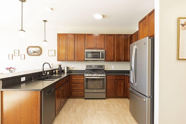 kitchen featuring a peninsula, a sink, appliances with stainless steel finishes, brown cabinets, and dark countertops