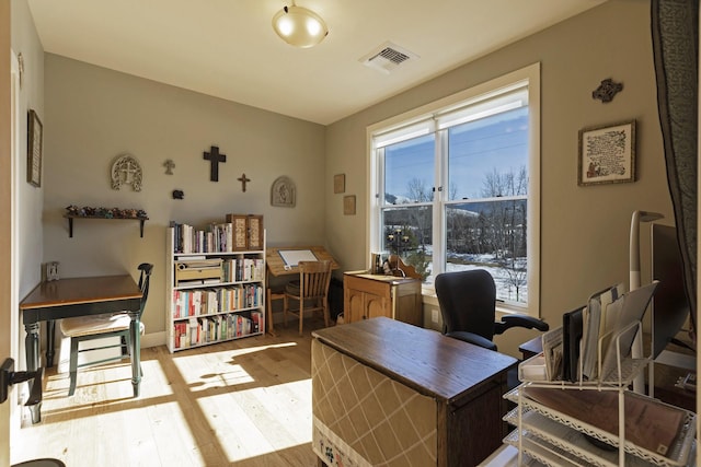 office space with light wood-type flooring, visible vents, and a wealth of natural light