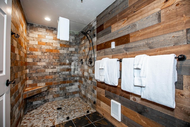 bathroom with tiled shower and visible vents