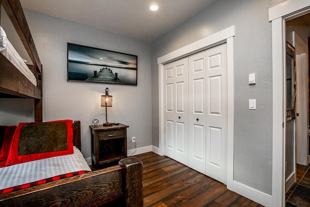 bedroom featuring a textured wall, dark wood-type flooring, a closet, and baseboards