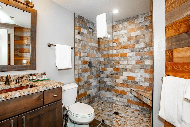 full bathroom featuring tiled shower, vanity, and toilet