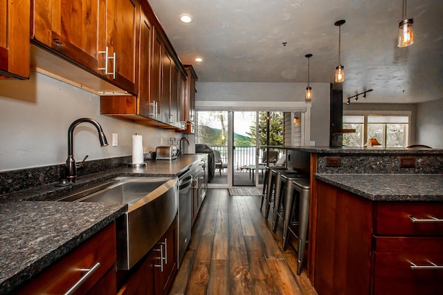 kitchen with dark wood-style flooring, recessed lighting, hanging light fixtures, stainless steel dishwasher, and a sink