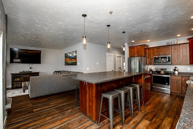 1400 Wisconsin Ave Unit 212, Whitefish, MT 59937 - kitchen with stainless steel appliances, dark countertops, dark wood finished floors, a kitchen island, and a kitchen bar