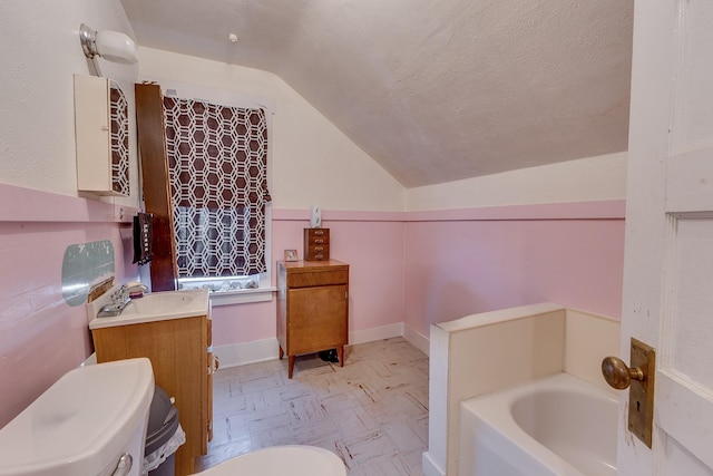 bathroom featuring toilet, lofted ceiling, a garden tub, a textured ceiling, and vanity