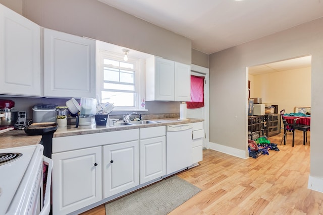 kitchen with white appliances, a sink, white cabinets, light countertops, and light wood-type flooring