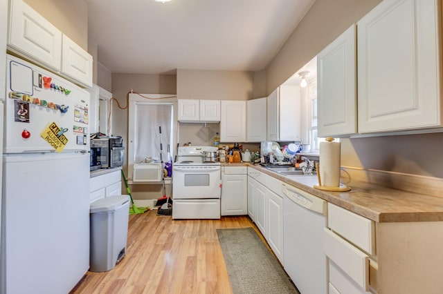 kitchen with white appliances, light countertops, light wood-type flooring, white cabinetry, and a sink