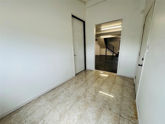 corridor with tile patterned floors, baseboards, and stairway
