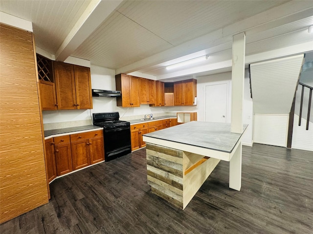 kitchen with dark wood-style flooring, light countertops, black gas range oven, brown cabinetry, and under cabinet range hood