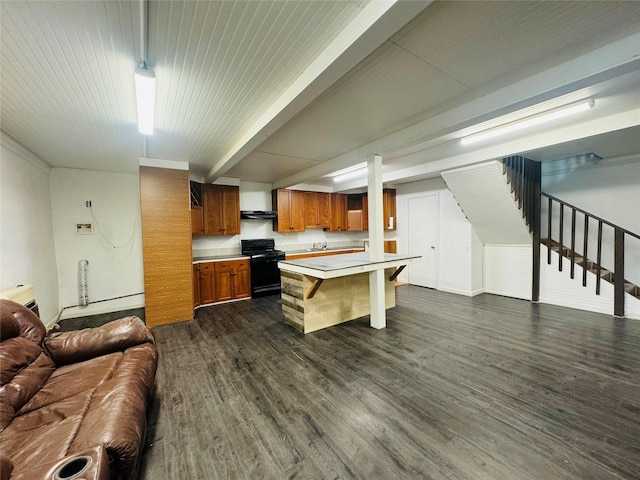 kitchen featuring black gas range, dark wood finished floors, a breakfast bar area, brown cabinets, and open floor plan