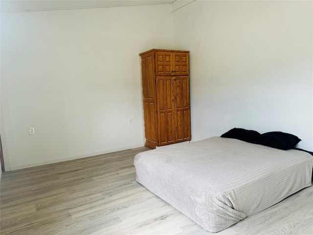 bedroom with light wood finished floors and baseboards