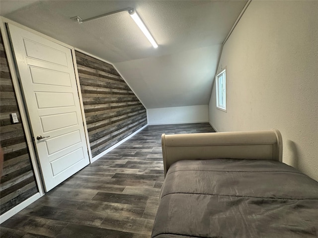 unfurnished bedroom with dark wood-style floors, lofted ceiling, and a textured ceiling