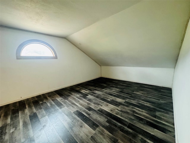 bonus room with dark wood-type flooring and lofted ceiling