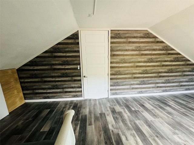 additional living space featuring wood walls, wood finished floors, and vaulted ceiling