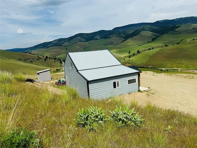 view of outbuilding with a rural view, a mountain view, and an outdoor structure