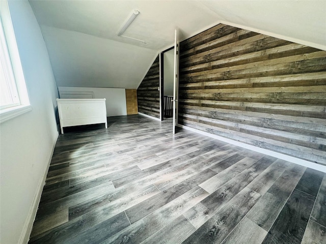 additional living space featuring wooden walls, baseboards, wood finished floors, and vaulted ceiling