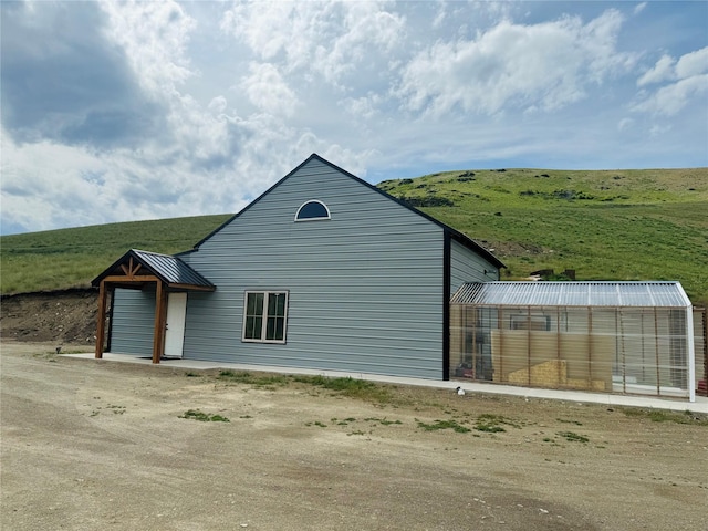 view of side of home featuring a greenhouse, metal roof, and an outdoor structure