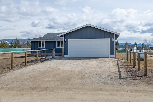 ranch-style home with a shingled roof, fence, dirt driveway, and a mountain view