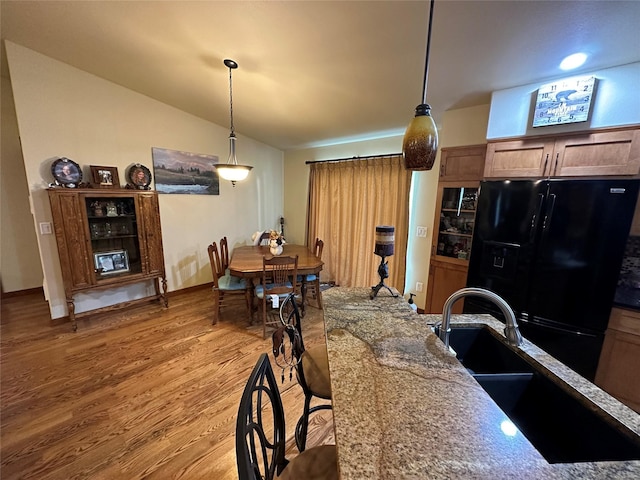316 3rd Ave, Saint Ignatius, MT 59865 - kitchen with black refrigerator with ice dispenser, lofted ceiling, light wood-type flooring, decorative light fixtures, and stone counters