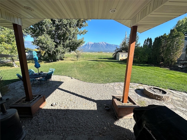 316 3rd Ave, Saint Ignatius, MT 59865 - view of grassy yard featuring a patio, a mountain view, a fire pit, and a storage unit