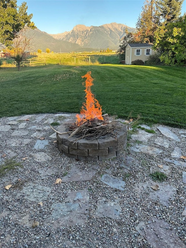 316 3rd Ave, Saint Ignatius, MT 59865 - view of green lawn with an outdoor fire pit, a storage shed, and a mountain view