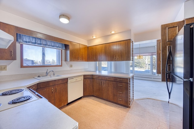 kitchen featuring white dishwasher, light countertops, a sink, and freestanding refrigerator