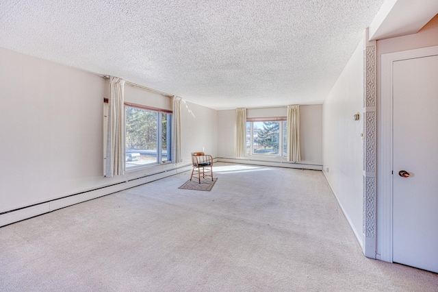 spare room with a textured ceiling, baseboard heating, and carpet flooring