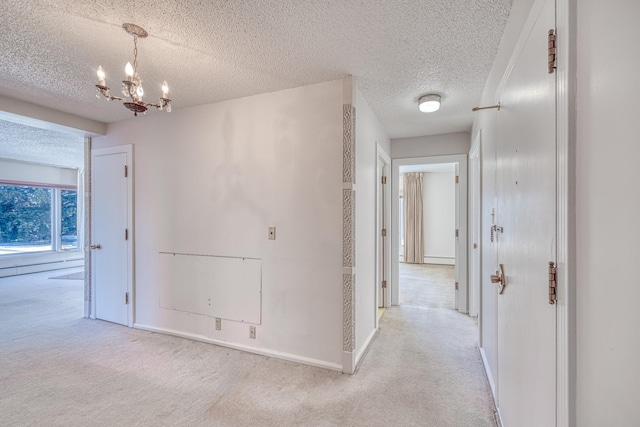 corridor with light colored carpet, a notable chandelier, a textured ceiling, and baseboards