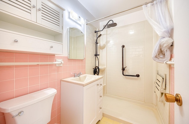 bathroom with toilet, tile walls, tiled shower, and vanity