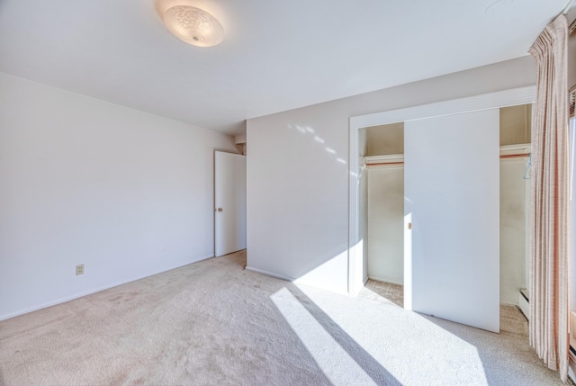 unfurnished bedroom featuring light carpet and baseboard heating