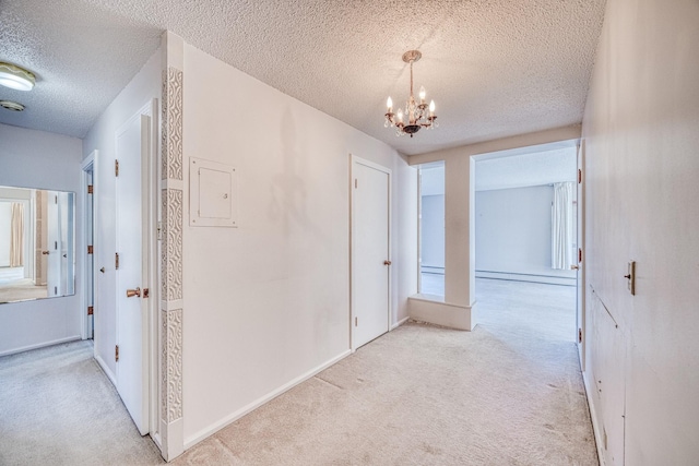 hall featuring a textured ceiling, a chandelier, a baseboard radiator, light carpet, and baseboards