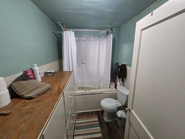 full bathroom featuring toilet, shower / bathtub combination with curtain, a textured ceiling, and wood finished floors