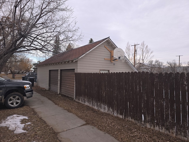 view of home's exterior with fence and an outbuilding