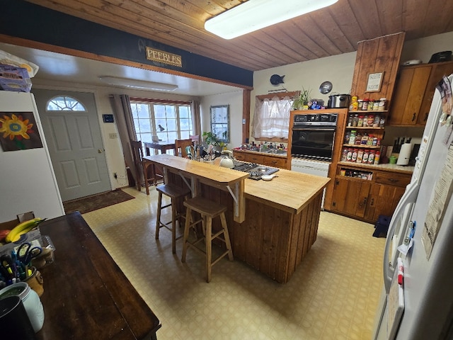 kitchen featuring stainless steel cooktop, light floors, wooden counters, and oven