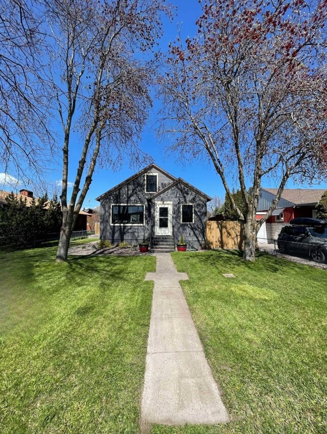 bungalow-style home with a front lawn and fence