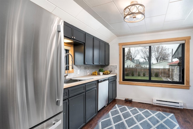 kitchen with decorative backsplash, dark wood-type flooring, stainless steel appliances, a baseboard heating unit, and a sink