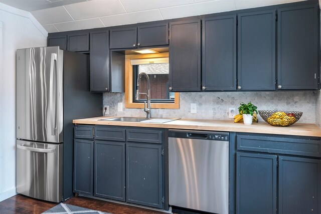 kitchen featuring light countertops, decorative backsplash, stainless steel appliances, and a sink