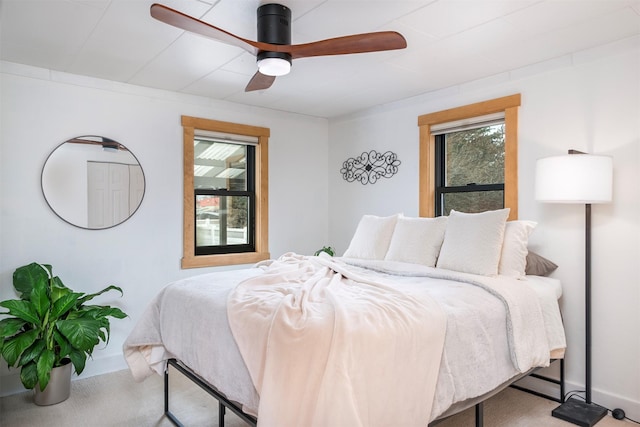 carpeted bedroom with multiple windows, ceiling fan, and baseboards