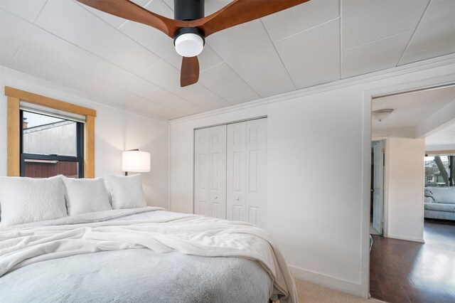 bedroom with ceiling fan, baseboards, wood finished floors, and a closet