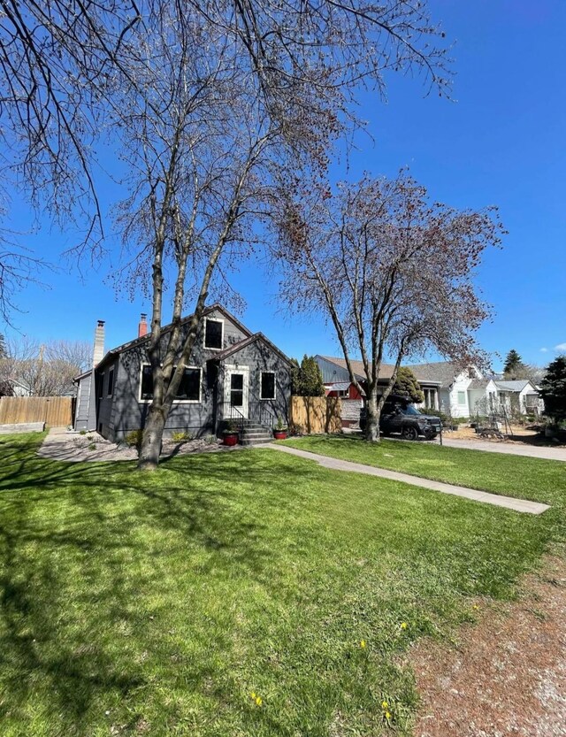view of front of house featuring fence, a front lawn, a chimney, and entry steps