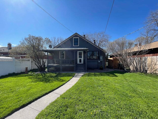 view of front of house featuring fence, covered porch, and a front yard