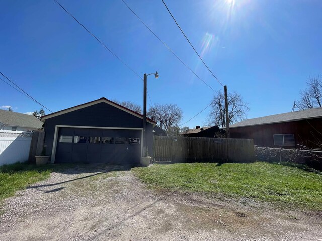 garage with dirt driveway and fence