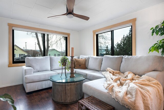 living area with baseboards, a ceiling fan, and dark wood-style floors
