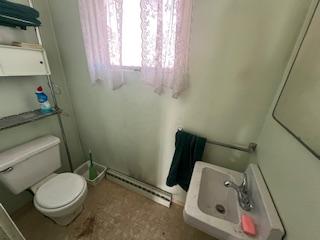 bathroom featuring a baseboard heating unit, a sink, and toilet