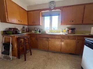 kitchen featuring light countertops, brown cabinets, dishwasher, and light floors