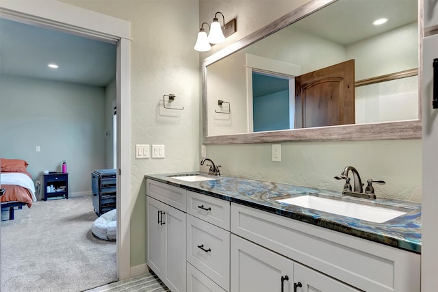 ensuite bathroom with baseboards, double vanity, a sink, and connected bathroom