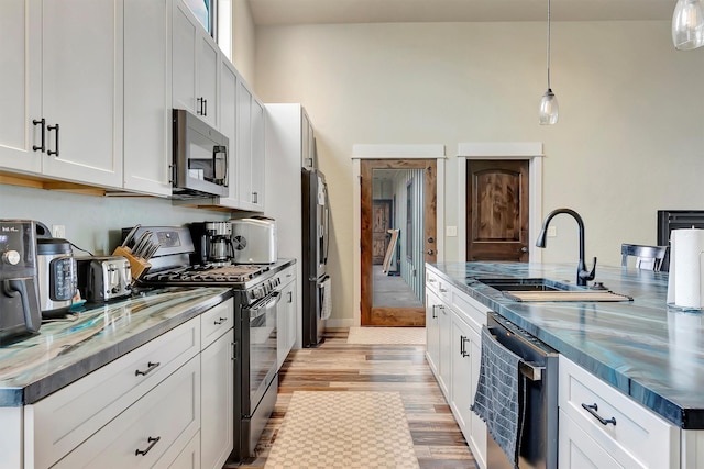 kitchen with light wood-style flooring, white cabinetry, stainless steel appliances, and a sink